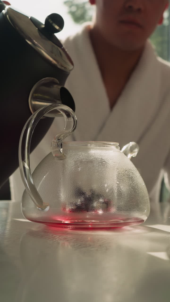 신사는 차병에 는 물을 부어주고, 돌보는 남자는 여름 휴가 동안 식탁 위에 과일 차를 기 위해 가열 된 액체로 비를 채니다.