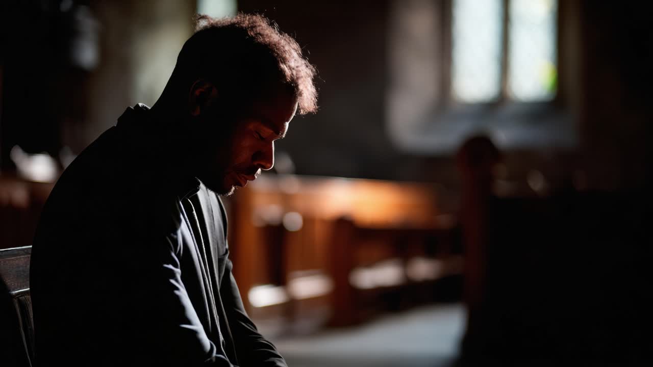 Un momento contemplativo: un uomo assorto in silenziosa riflessione all'interno di una chiesa scarsamente illuminata, che enfatizza la profondità delle emozioni umane e della spiritualità in un ambiente sereno