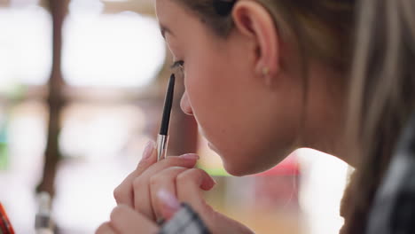 aerial view of young lady applying eye pencil on eyelid, focusing on precise makeup application, the close-up captures delicate cosmetic process and attention to detail in eye makeup routine