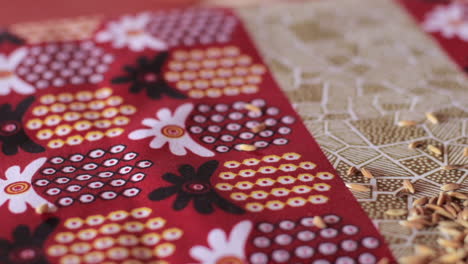 panning shot of unhusked rice on african dashiki cloth backdrop