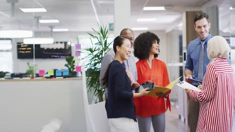 Group-of-diverse-business-people-holding-documents-and-talking-in-office,-slow-motion