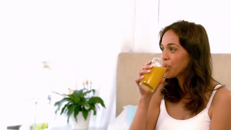 mujer feliz con jugo de naranja en la cama