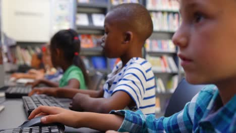 Side-view-of-mixed-race-schoolkids-studying-on-computer-in-the-classroom-4k