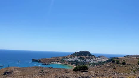 Lindos-beach-overlooking-Acropolis-ruins-Castle-in-Rhodos,-Greece,-travel-destination-filmed-in-4K-during-the-day
