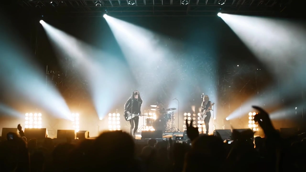 Esibizione dal vivo di una rock band sul palco con luci intense e folla esultante
