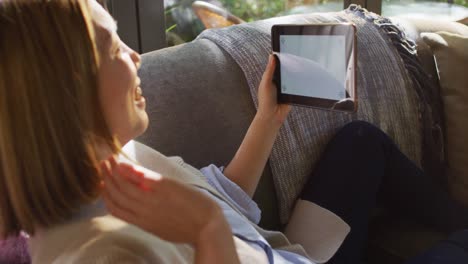 asian woman lying on couch and using tablet with copy space