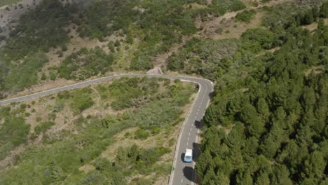 aerial shot of beautiful vw camper van driving down a scenic mountain road in madeira