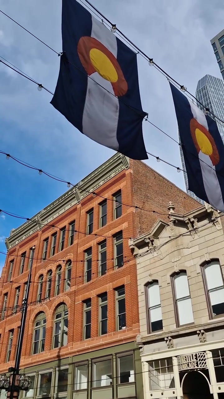 Vista verticale delle bandiere dello Stato del Colorado e di vecchi edifici su Larimer Square, Denver, USA