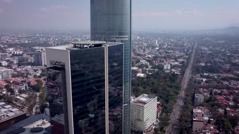 Panoramic-view-of-the-south-of-Mexico-City,-in-the-foreground-appear-a-couple-of-modern-skyscrapers,-the-pollution-hides-the-horizon-of-the-vast-city