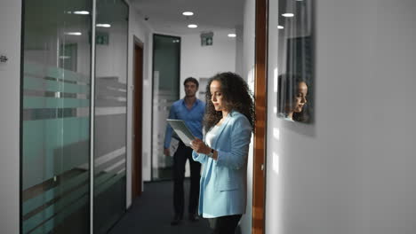 Latin-employee-working-tablet-corridor-closeup.-Cheerful-man-say-hello-on-go