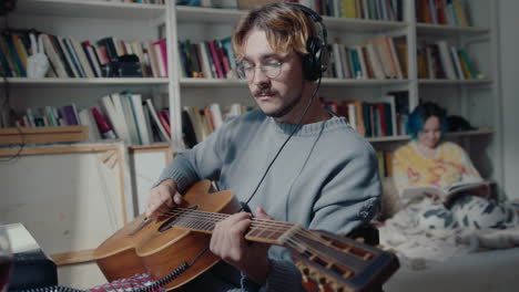 man in headphones playing the guitar at home music studio