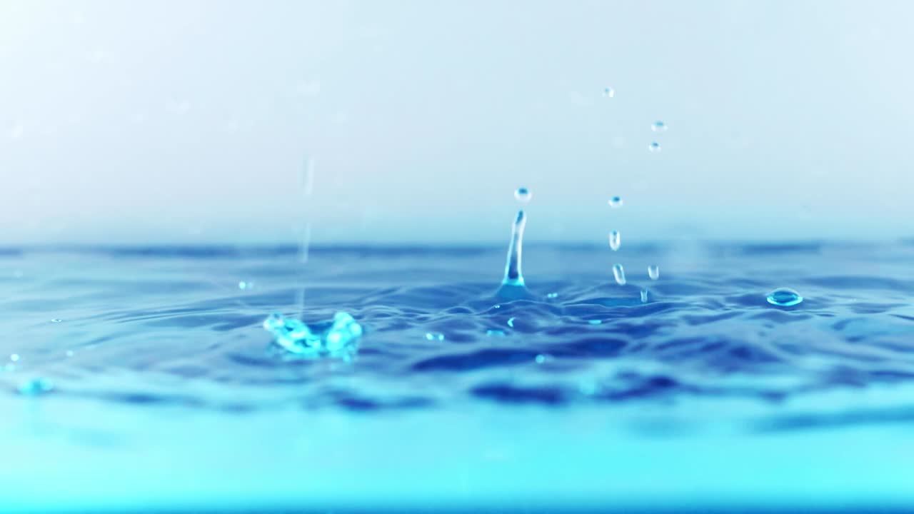 슬로우 모션의 깨끗한 물 표면은 물이 튀는 상점으로 화면을 채우고 기포로 액체 표면을 흔들고 있습니다.
