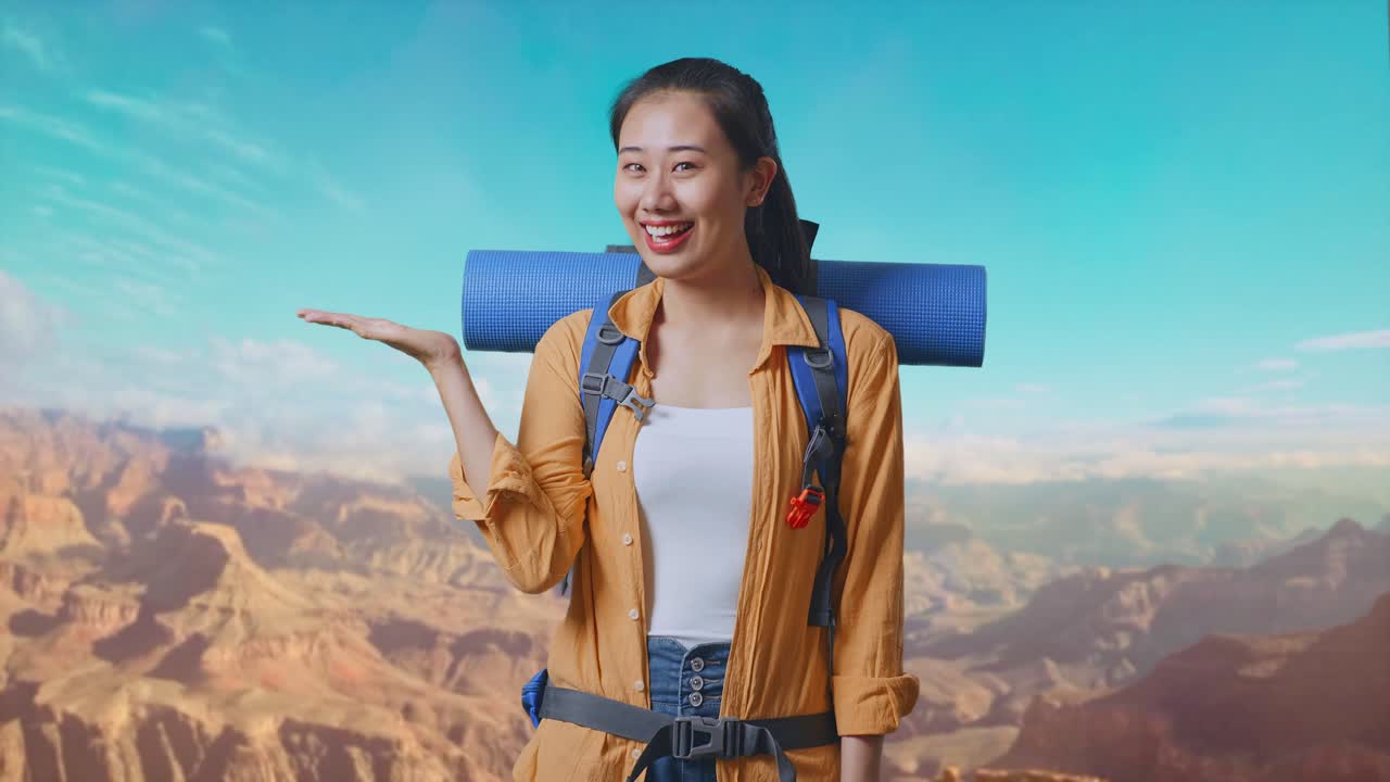 Asian Female Hiker With Mountaineering Backpack Smiling And Pointing To Side While Traveling At The Top Of Mountain