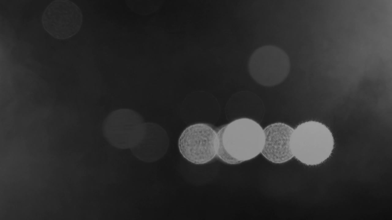 Soft blurred light circles from moving cars drifting through foggy night atmosphere