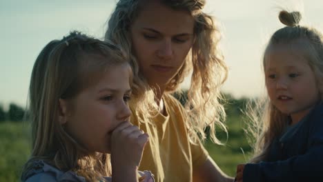 Mom-with-two-little-daughters-talking-together-at-the-meadow.