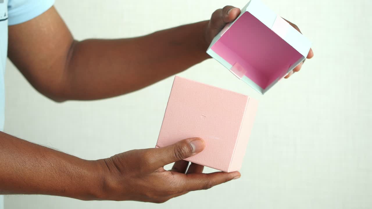 hombre abriendo una caja de regalo rosa vacía
