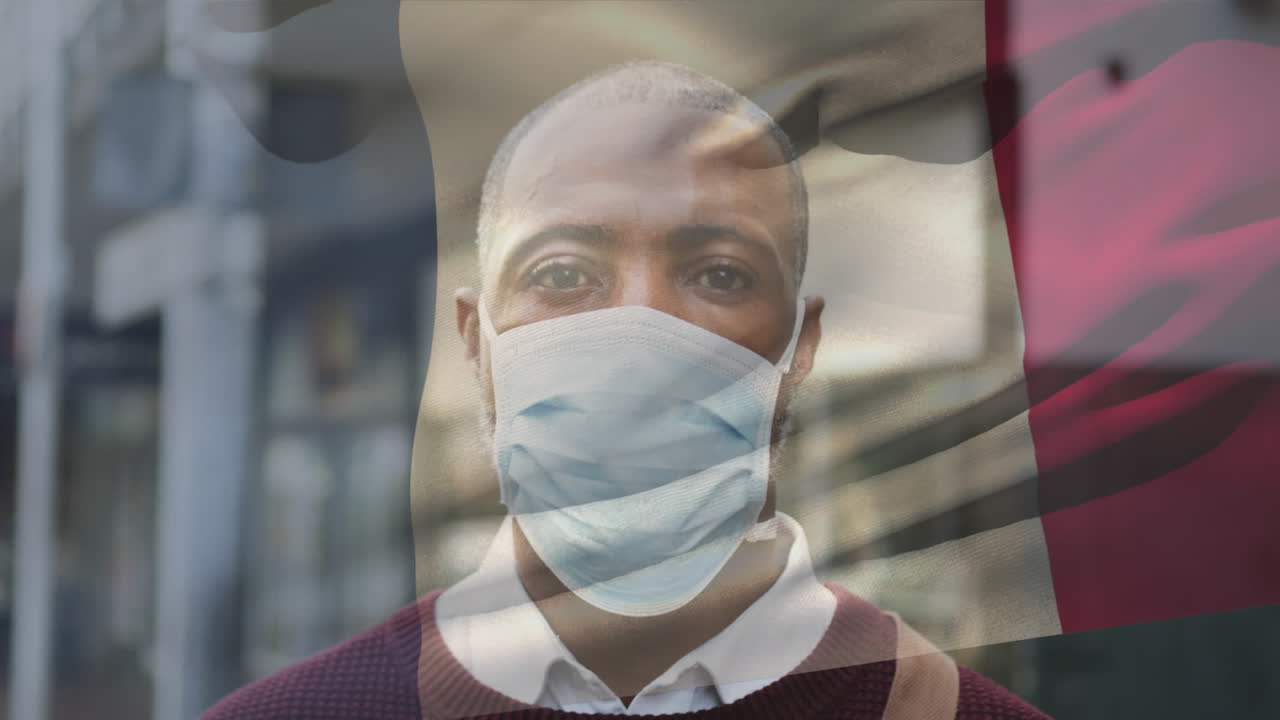 Animation of flag of france waving over man wearing face mask during covid 19 pandemic