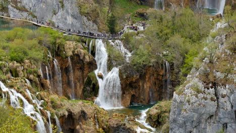 vista panorámica del parque nacional de los lagos de plitvice en croacia, turistas caminando por el camino del puente de madera