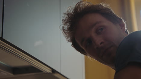 man looking under kitchen cabinet