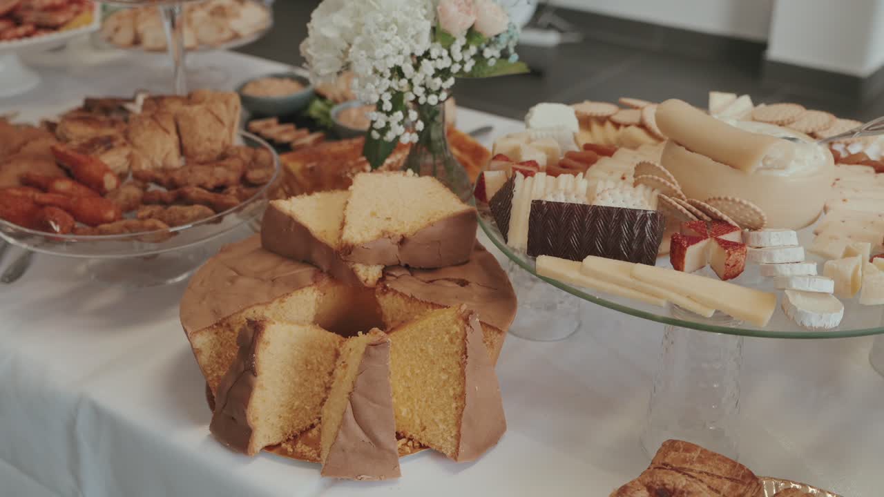 치즈 플래터와 장식된 뷔페 테이블 위에 놓인 슬라이스 스펀지 케이크