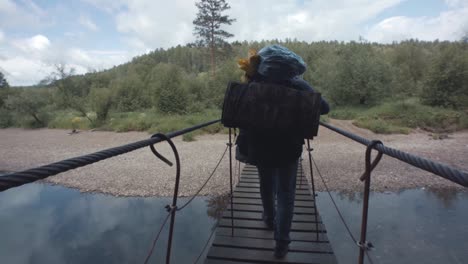 hiker crossing a bridge over a river