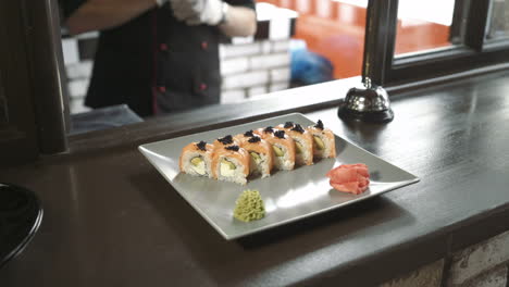 professional chef in a commercial kitchen in a restaurant or hotel is serving sushi rolls