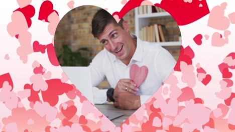 Animation-of-heart-shaped-frame-with-red-hearts-flying-over-caucasian-man-on-laptop-video-call