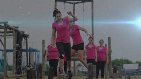 balancing on outdoor obstacle course, women in pink shirts showing determination