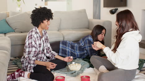 women friends enjoying popcorn and hot chocolate at home, sharing cozy moments together