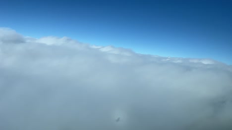 vista aérea, punto de vista piloto, del halo de un avión a reacción que sobrevuela las nubes durante un giro a la izquierda con un cielo azul profundo
