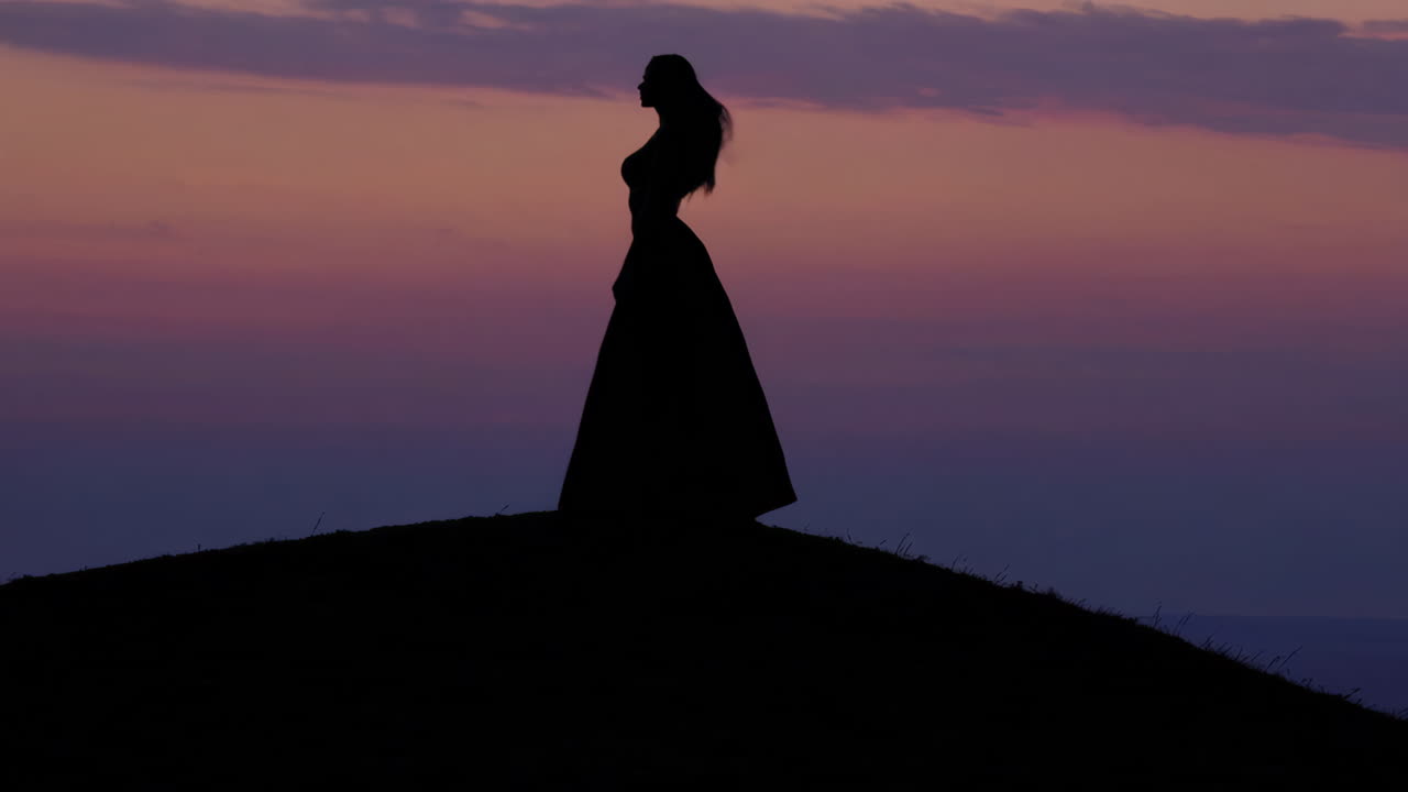 Silhouette of Woman on Hill at Sunset