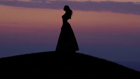 silhouette of woman on hill at sunset