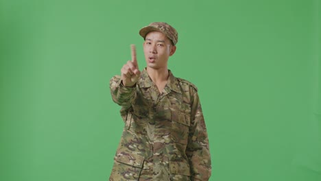 Asian Man Soldier Pointing At You And Disapproving With No Index Finger Sign While Standing In The Green Screen Background Studio