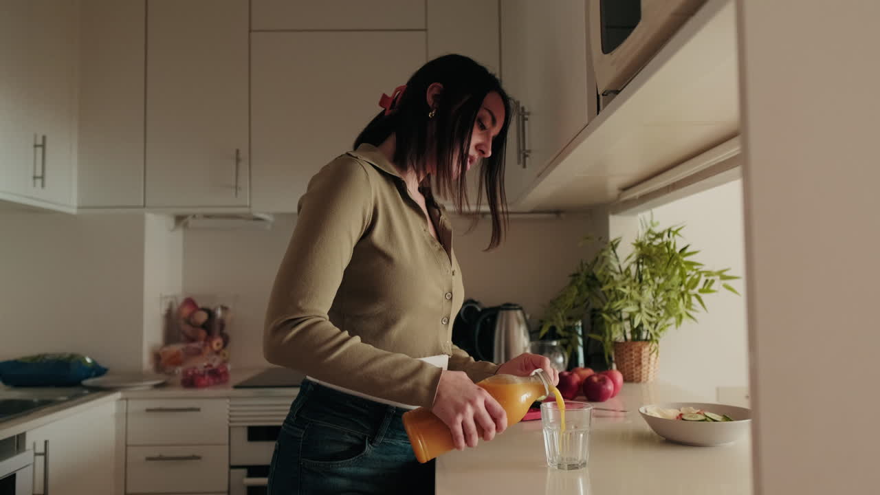 Donna versa succo d'arancia in una cucina moderna. Foodblog