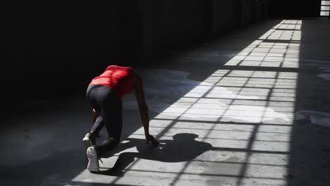 hombre afroamericano arrodillado comenzando una carrera en un edificio vacío