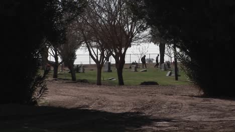 two people are walking and looking at gravestones in a cemetery by the sea