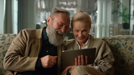 Aufgeregtes-älteres-Paar,-Das-Zu-Hause-Videoanrufe-Auf-Dem-Tablet-Computer-Tätigt