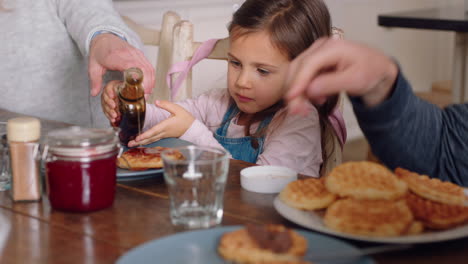 happy family eating breakfast waffles with children enjoying delicious treat in kitchen at home