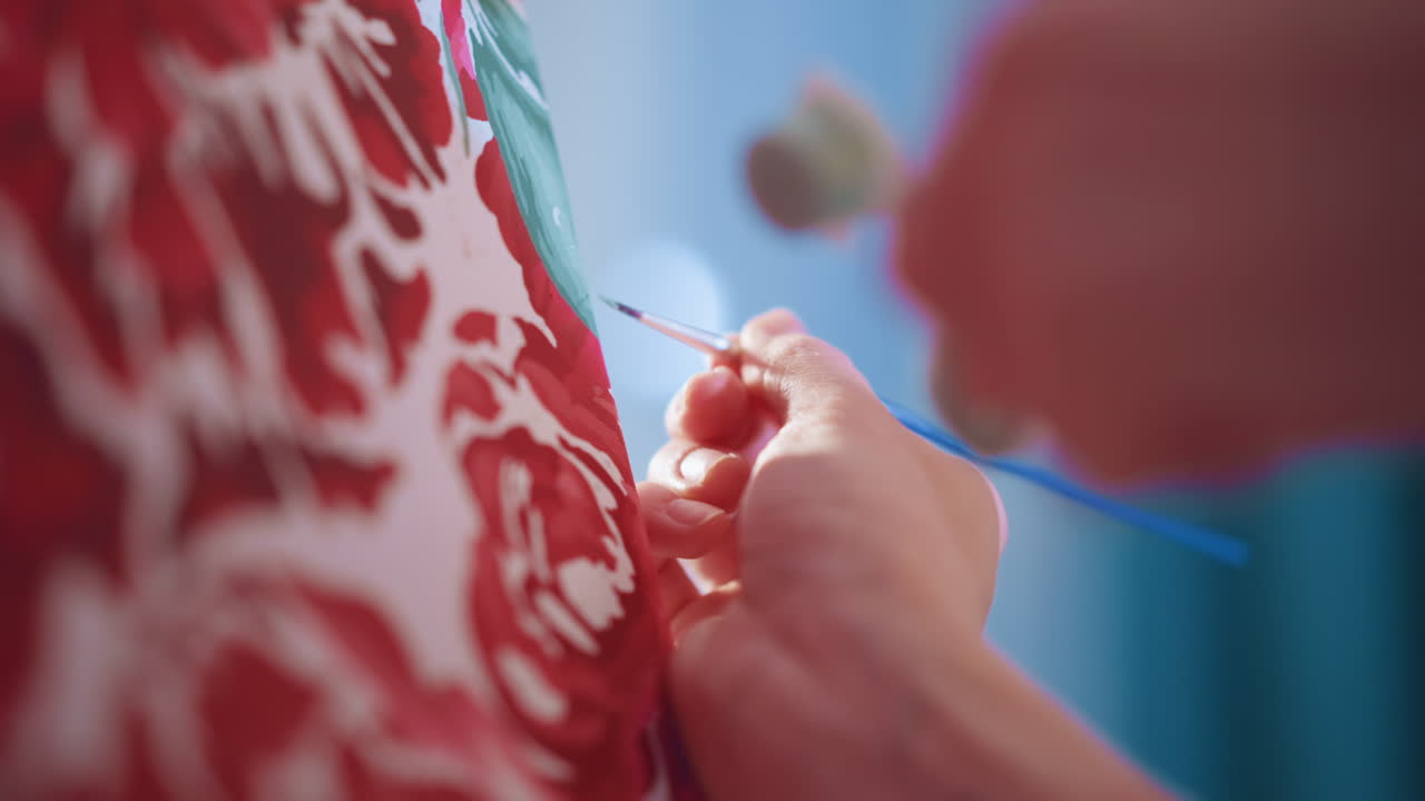 Closeup White Hands Painting Leaf Detail On Floral Canvas, Cool Daylight, Tiny Brush Strokes, Careful Layering Of Greens, Roller Tool In Background, Patient Technique, Intimate Craft Moment