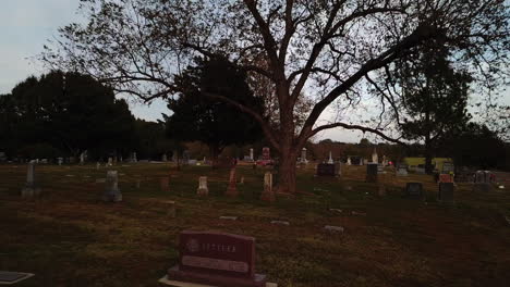 Aerial-drone-backward-moving-shot-over-a-burial-ground-in-Tulsa,-Georgia-during-evening-time