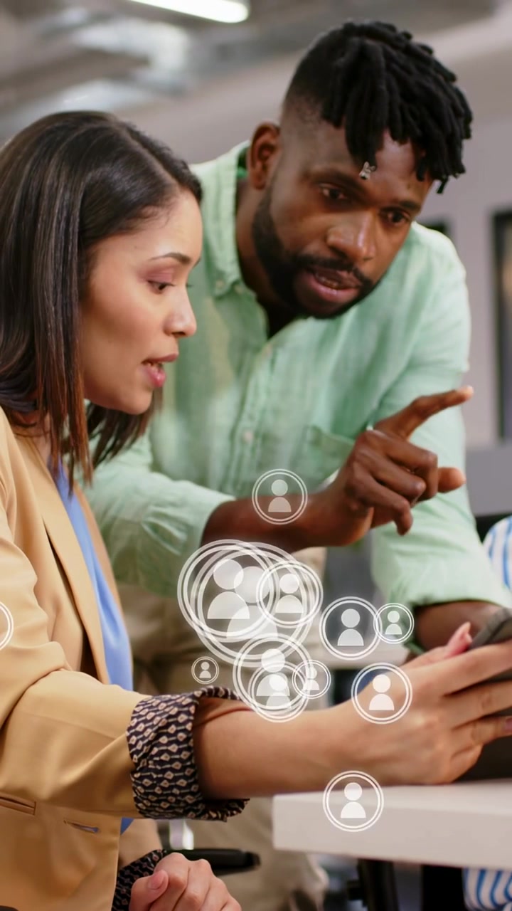 Vertical video: Woman tapping tablet, standing man pointing, creating UI nodes for business
