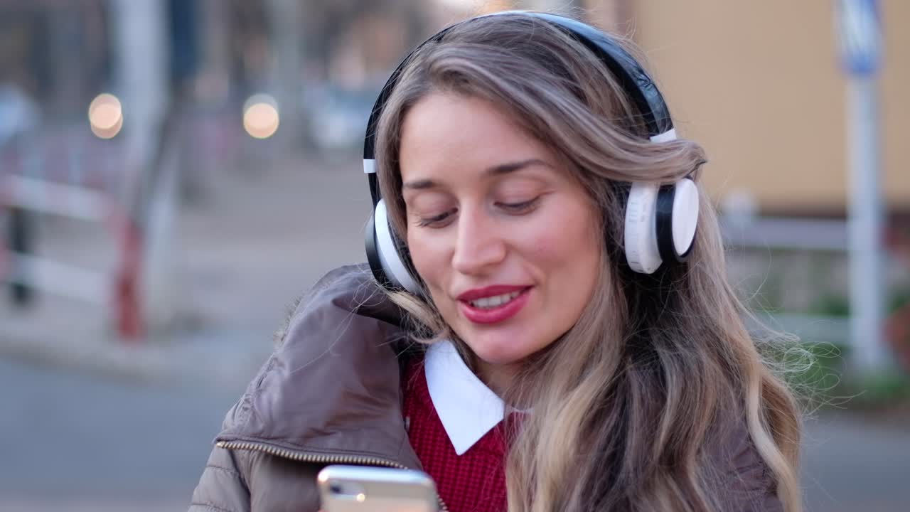 Woman listening to music in her headphones while singing along and dancing in the street