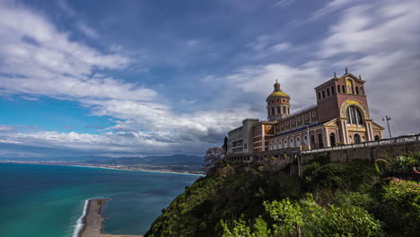 Lapso-De-Tiempo-En-La-Nube-Con-Una-Hermosa-Catedral-En-Primer-Plano-Y-La-Costa-Del-Mar-En-Segundo-Plano-En-La-Basílica-Santuario-Maria-De-Tindari-En-Italia