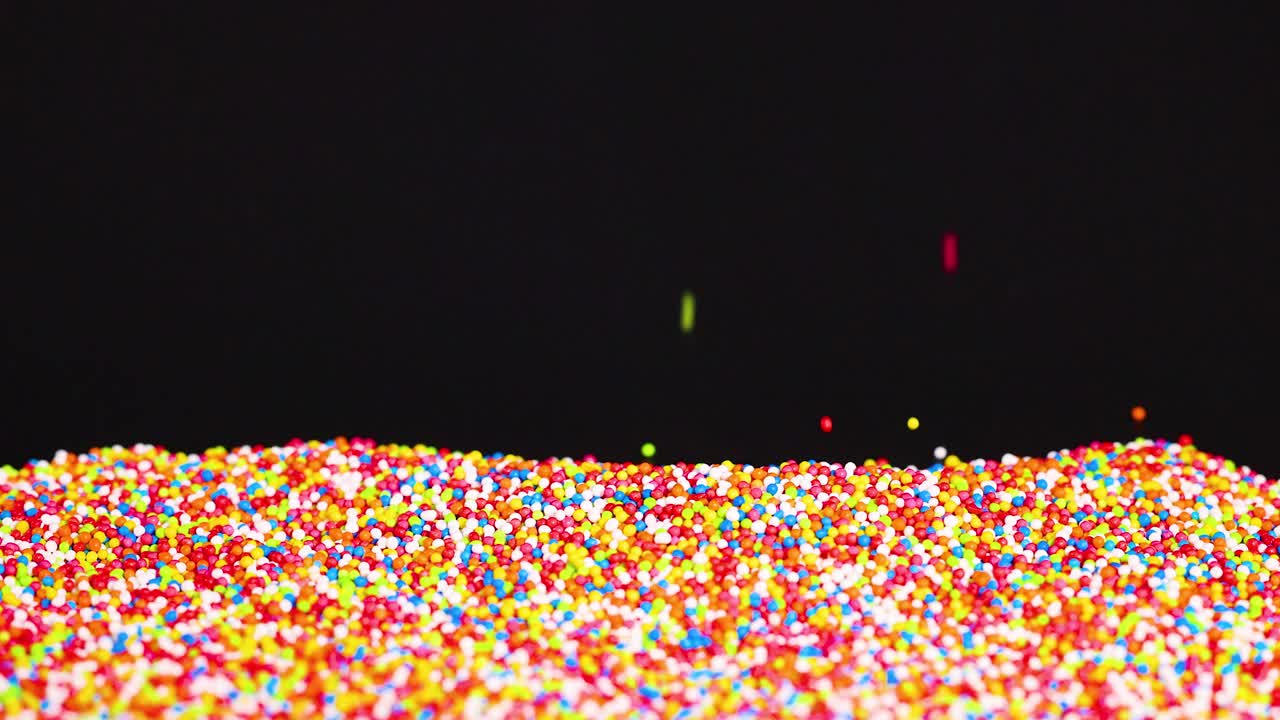 Sprinkles cascade onto a growing pile