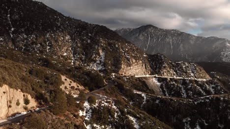 Drone-flying-towards-a-road-in-a-snowy-mountain