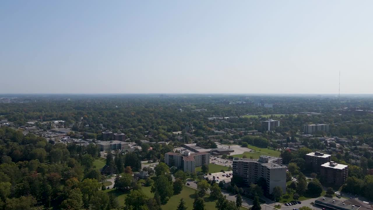 나무와 아파트 건물을 보여주는 맑고 흐릿한 런던 교외 상공을 비행