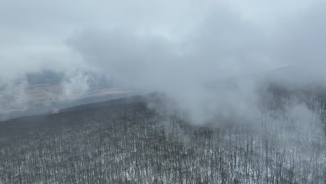 high altitude drone flight in the clouds over winter mountain