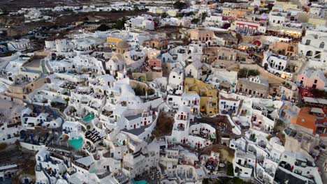 Oia-village-cliffside-houses-and-hotels-in-Santorini,-Greece,-Cinematic-aerial-view