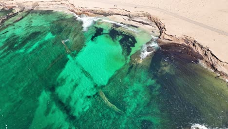 Pequeña-Playa-Escondida-Playa-De-Los-Ojos-Con-Algunas-Personas-Muy-Lejos