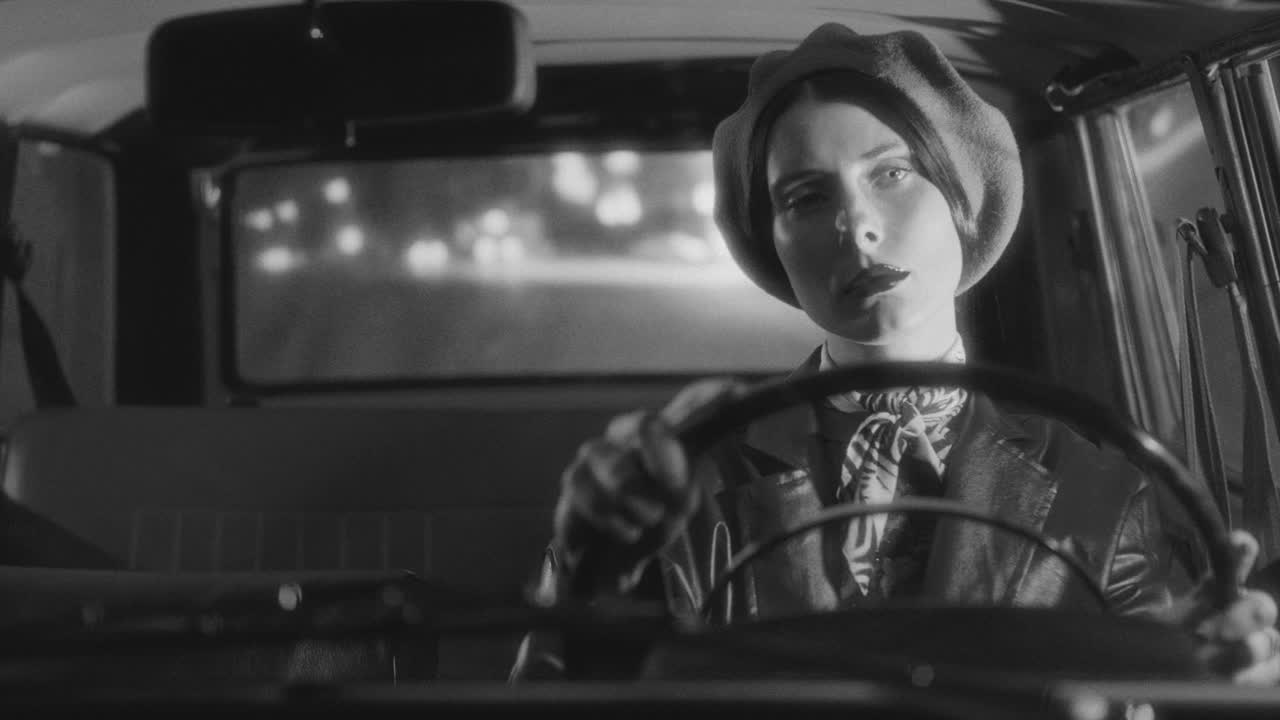 Black and White Portrait of Elegant Woman Driving Vintage Car at Night